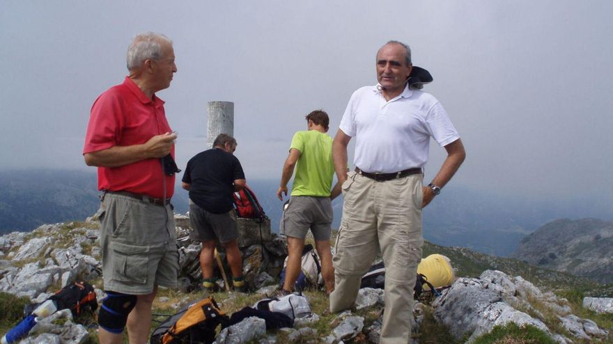 En la cima del Jorcáu del Cuernu. En primer término, Oscar Arias y Pedro Rodríguez Inciarte. Junto al vértice geodésico, José Manuel González Antón y Luis Velasco. En la foto de la derecha, cumbres del Macizo Central de los Picos pugnan por hacerse ver entre las nubes: Peña Castil, el Picu Urriellu, el Neverón de Urriellu y los Albos. | M. F. D.