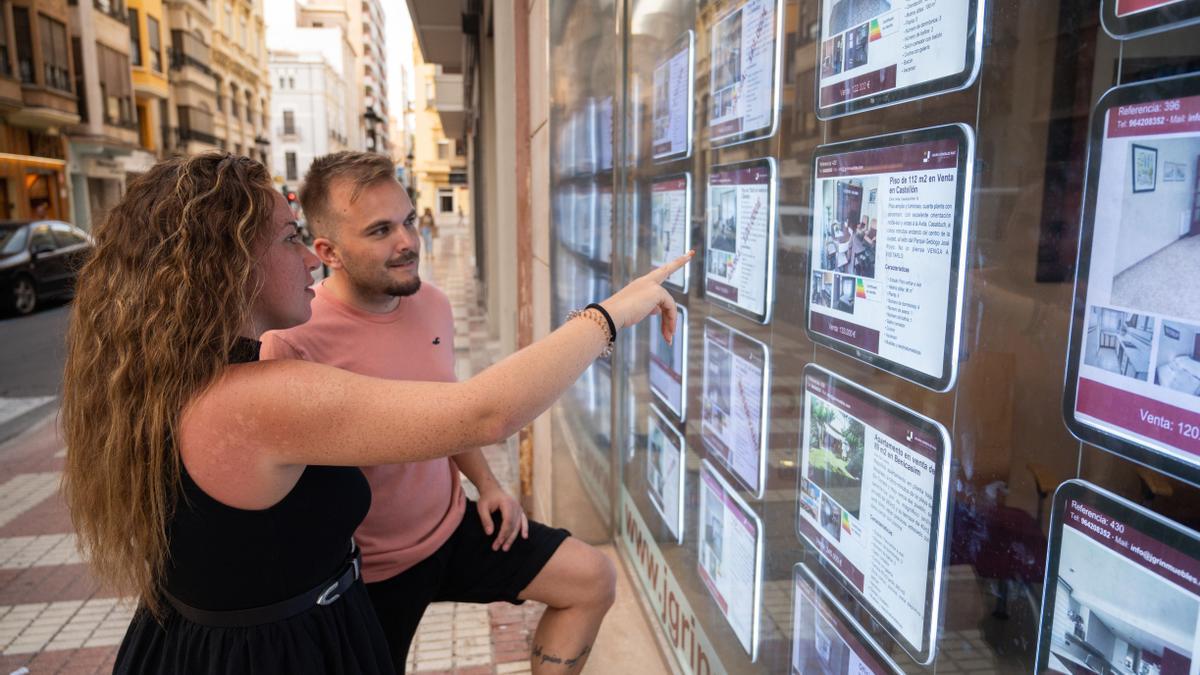 Dos jóvenes observan ofertas de viviendas en una agencia inmobiliaria situada en el centro de Castelló.