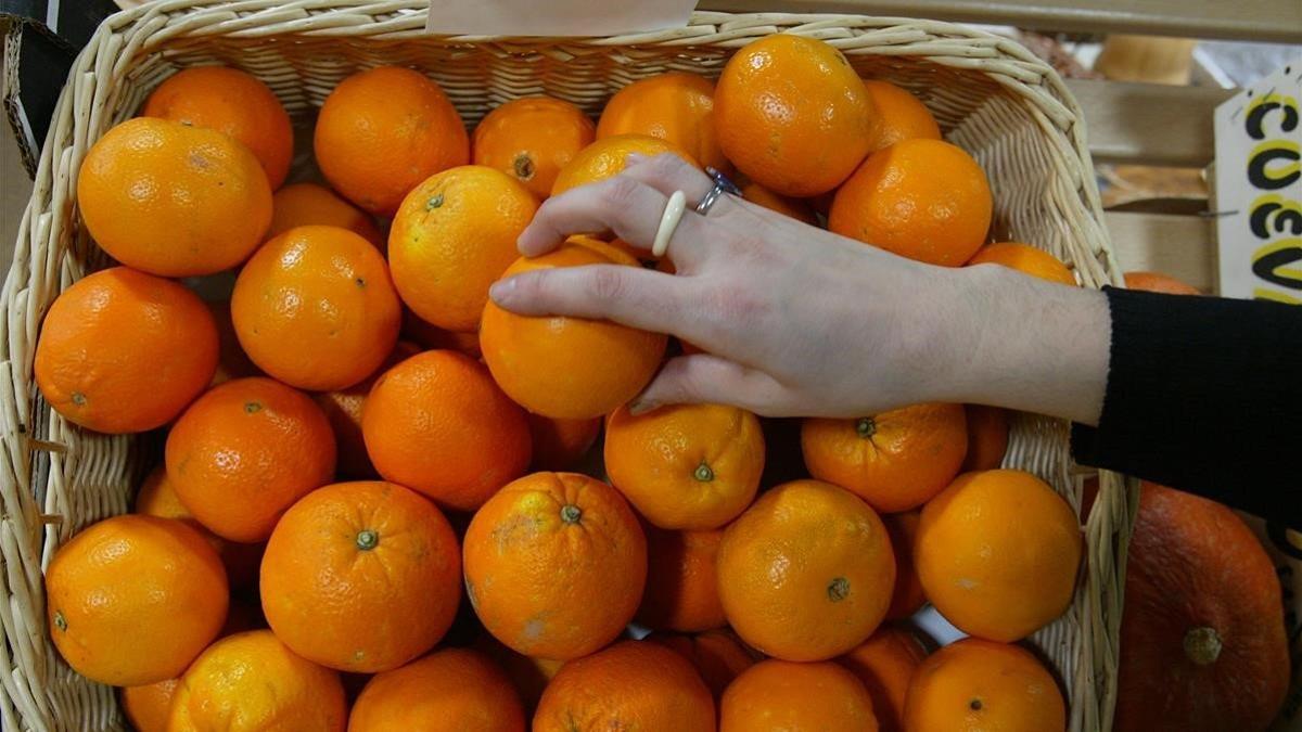 Una persona coge una naranja en un supermercado