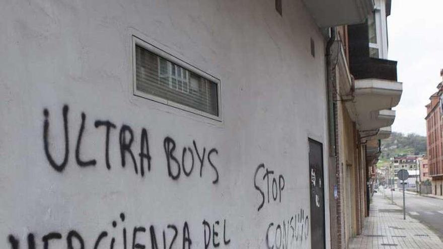 Uno de los bajos con pintadas que el Ayuntamiento ha reclamado limpiar, en una calle de El Entrego.