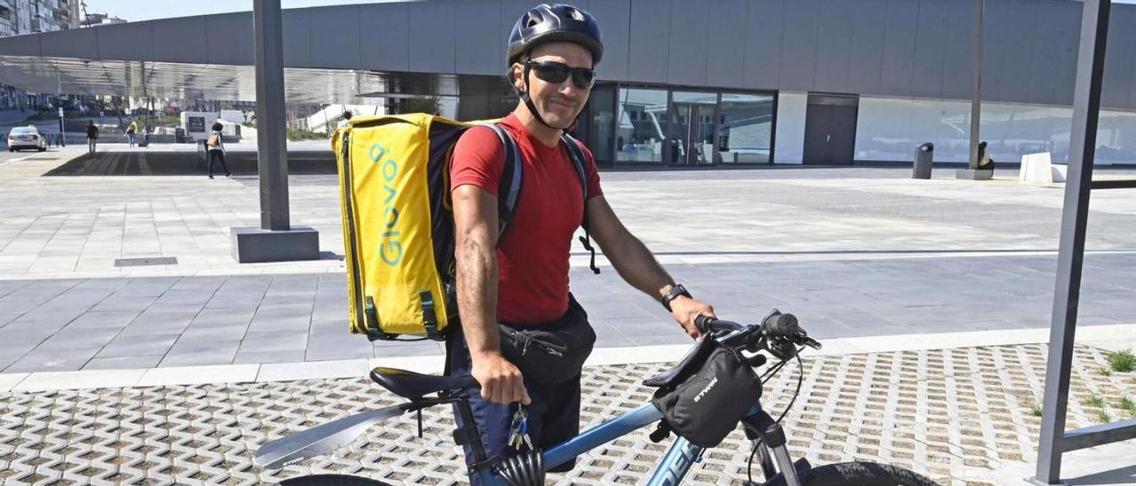 David Conguta junto a su bicicleta y la mochila de Glovo delante de Vialia Vigo.