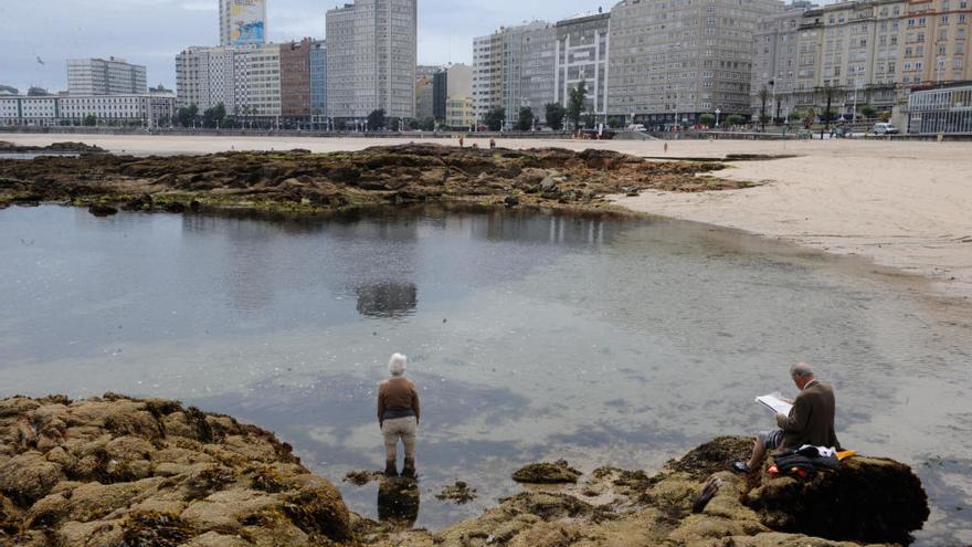 Bañistas en Riazor un día nublado de verano.