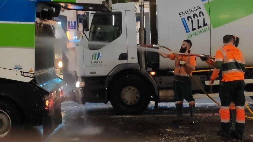 Operarios de Emulsa apagan el fuego en uno de los vehículos con una manguera en la calle Marqués de San Esteban.