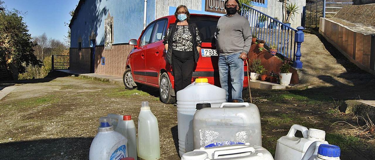 Conchita Vega y Pedro Rodríguez, ante su casa de Hevia (Siero), con las garrafas que tienen que usar a diario. | A. I.