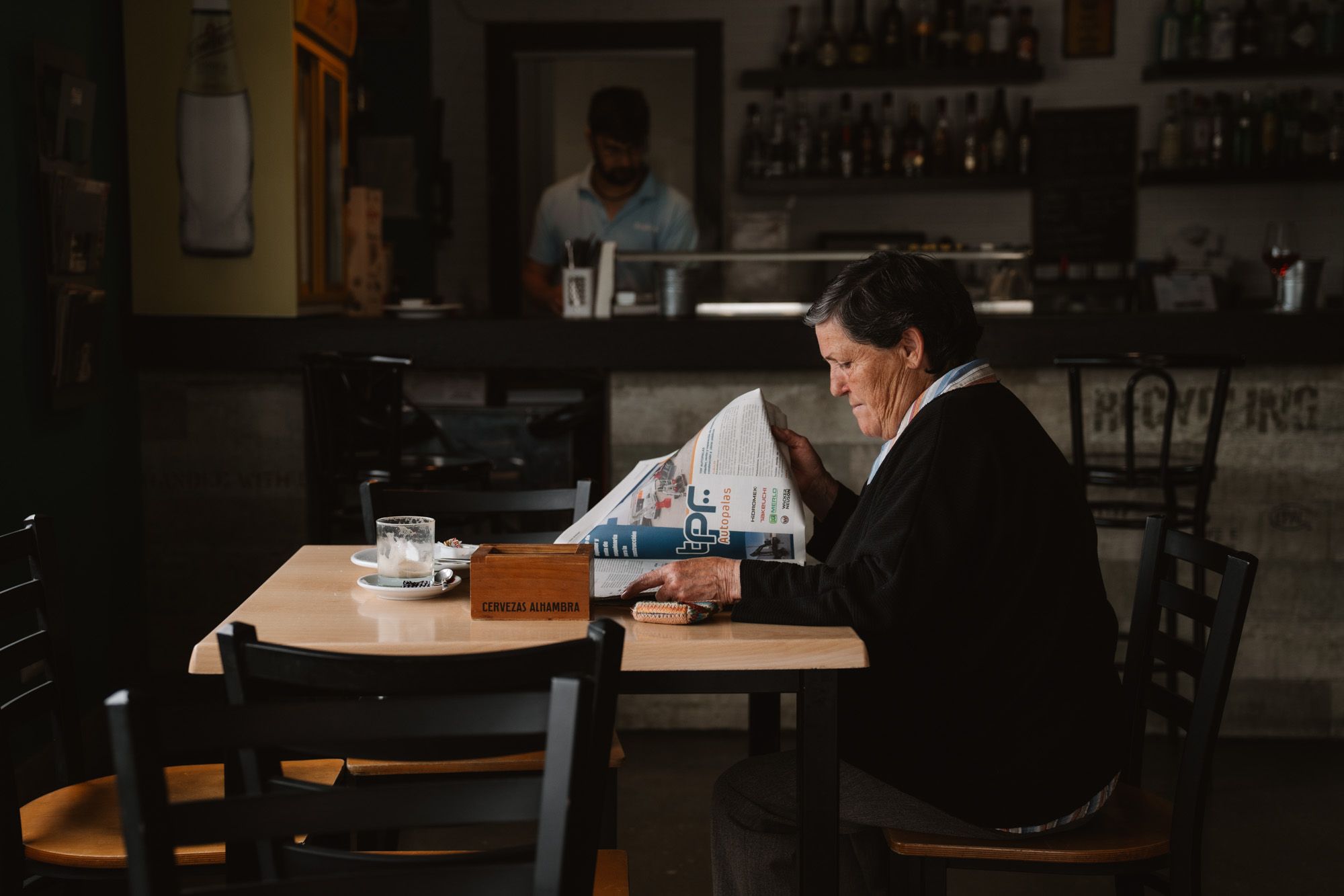 Una vecina de Anguix lee el periódico en BarBecho, uno de los tres establecimientos de hostelería del pueblo.