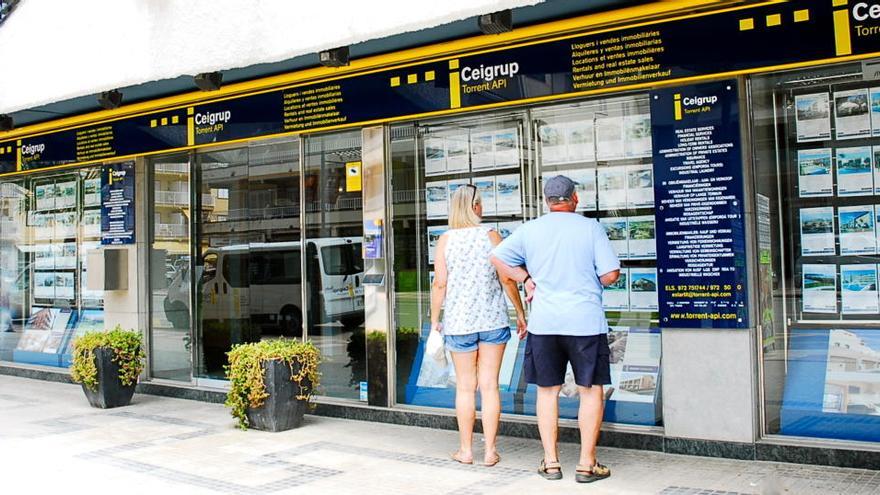 Una parella mira ofertes d&#039;immobles penjades en una oficina de la immobiliària gironina Ceigrup ell mes de juny del 2020