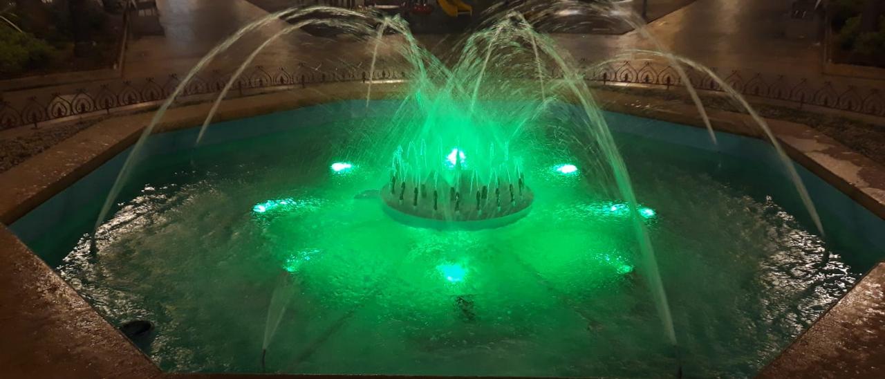 La fuente de la Plaça Major iluminada de verde por el Día Internacional de la Miastenia
