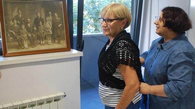Fe Santoveña ajusta la manta a una colaboradora, con una foto de 1922 como referencia.