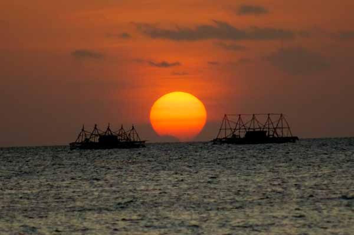 Las plataformas flotantes de pesca cobran vida al atardecer.