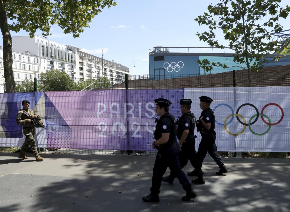 A soldier and police officers patrol by Paris 2024 Olympic banners, just nine days before the start of the Paris Olympic games, Wednesday, July 17, 2024 in Paris. (AP Photo/Aurelien Morissard) / EDITORIAL USE ONLY / ONLY ITALY AND SPAIN