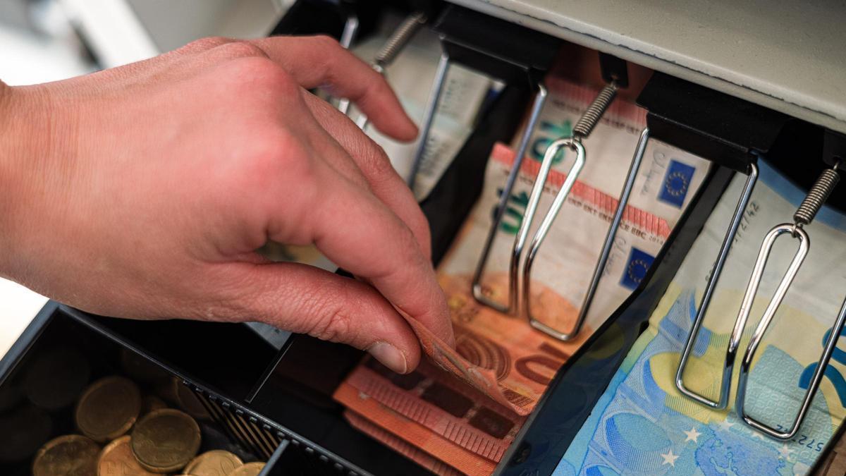 Una mà agafa bitllets i monedes en una caixa