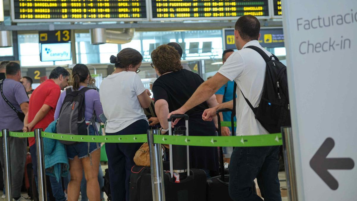 Pasajeros hacen cola en un aeropuerto.