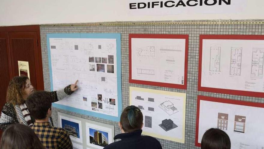 Una profesora explica a un grupo de alumnos del instituto un panel de la exposición de Obra Civil y Edificación del Fernández Vallín.