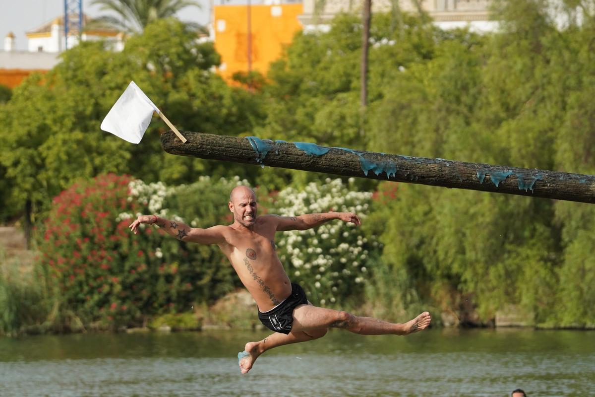 La 'cucaña', el juego centenario que regresa cada verano al río Guadalquivir por la Velá de Santa Ana en imágenes