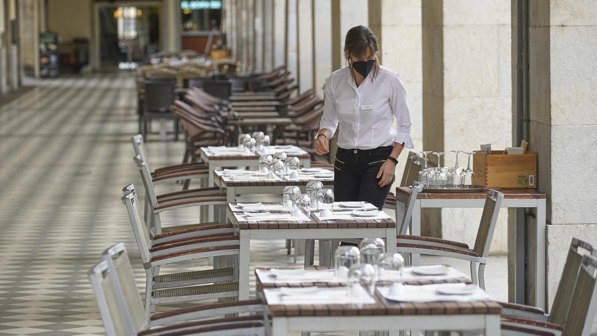 Una cambrera parant una taula a Girona.