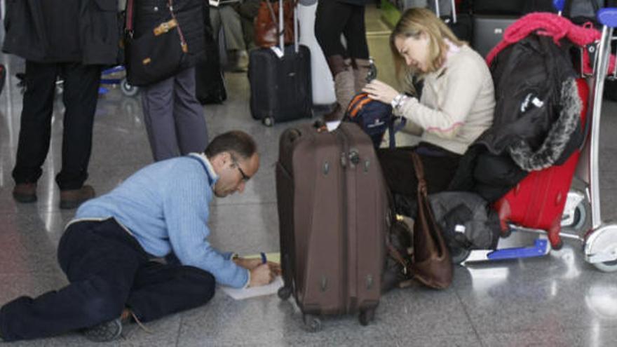 Una pareja rellena una hoja de reclamaciones tras verse afectados por la huelga en el aeropuerto de Málaga.