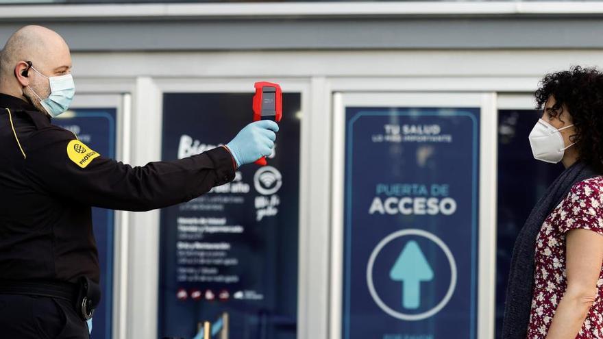 Un miembro de los servicios de seguridad toma la temperatura a una persona.