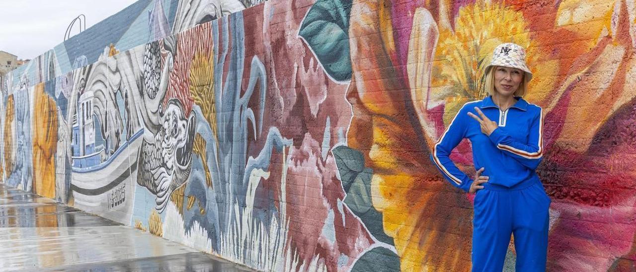 La muralista Lula Goce posa junto a su mural en Baiona.