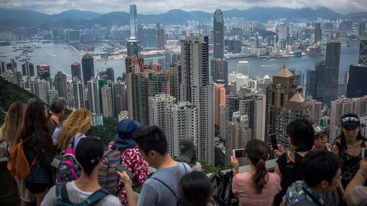 Turistas hacen fotografías desde el Victoria Peak a los edificios comerciales y residenciales situados a ambos lados del puerto de Victoria, en Hong Kong.