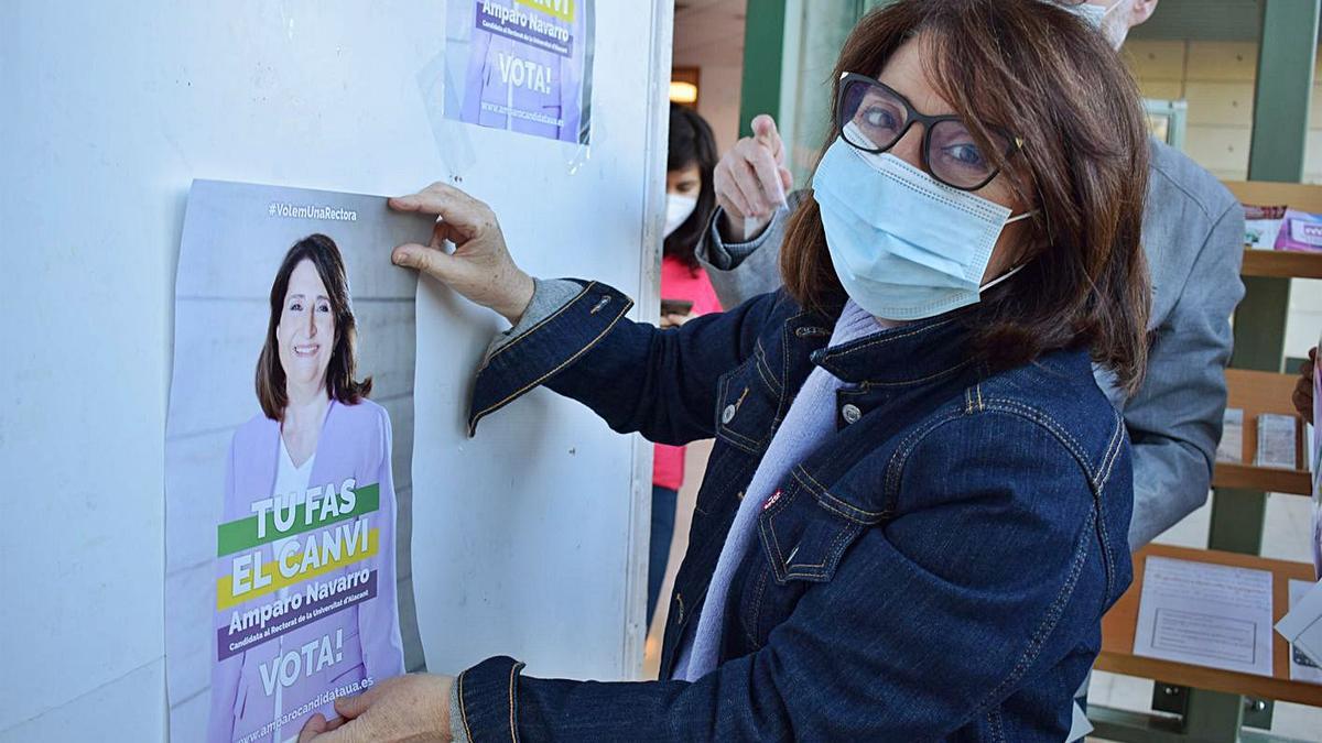 Navarro coloca uno de los carteles de campaña en el campus de la UA. |