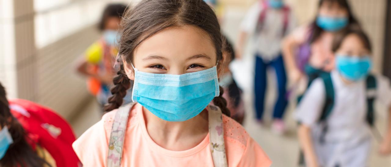 Una niña con mascarilla en el colegio.