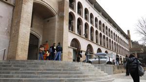 La puerta de la Facultad de Letras de la UdG con algunos estudiantes hablando en las afueras