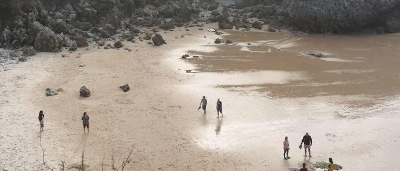 Surfistas y paseantes, ayer, en la playa llanisca de Portiellu.