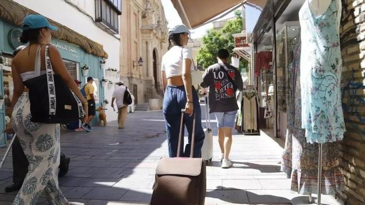 Turistas caminan con sus maletas por la calle Jesús y María de Córdoba.