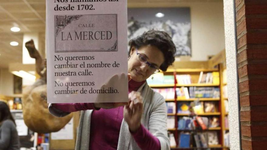 Isabel de la Rosa fija el cartel reivindicativo en la librería Cornión.