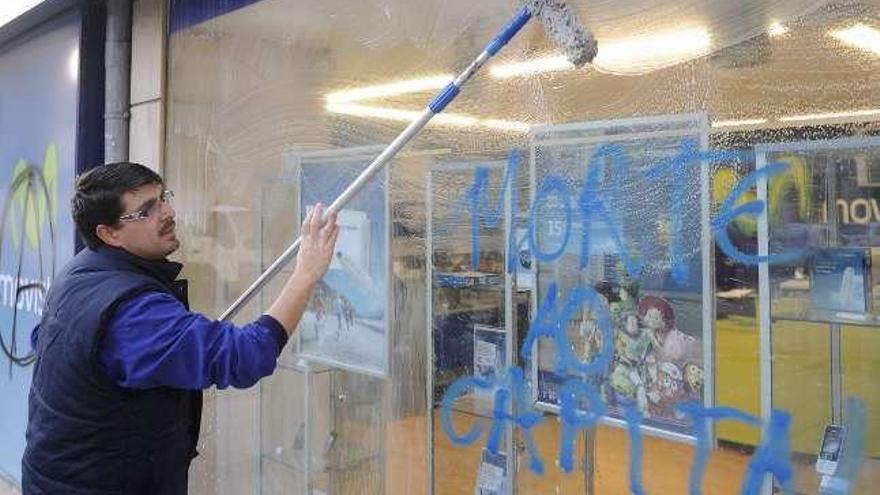 Un operario limpia el escaparate de una tienda de Movistar. / C. Pardellas / N. Prada