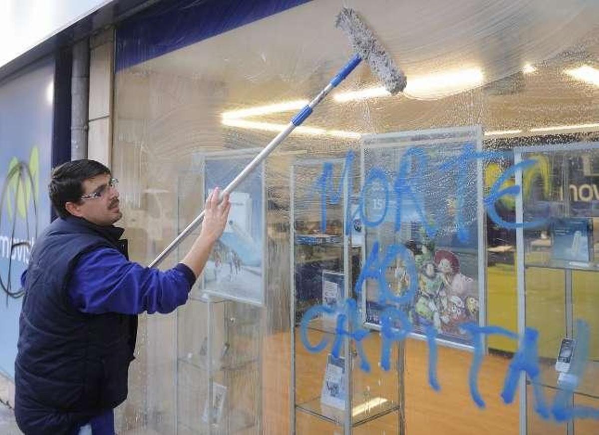 Un operario limpia el escaparate de una tienda de Movistar. / C. Pardellas / N. Prada