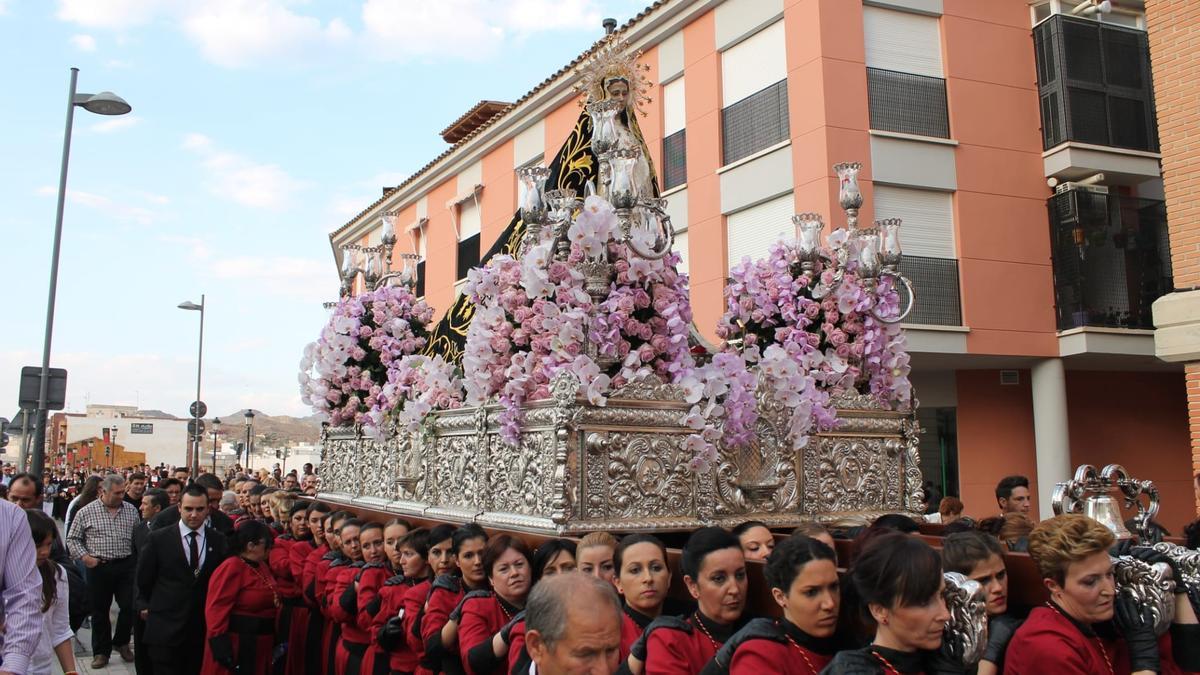 María Dolores Chumilla a mitad del varal izquierdo de la Virgen de la Soledad, del Paso Encarnado, tras cruzar el Puente Viejo del Barrio camino de la ciudad para participar en los Desfiles Bíblico Pasionales de Viernes Santo.