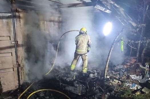 Un bombero sofocando el fuego que calcinó el almacén.