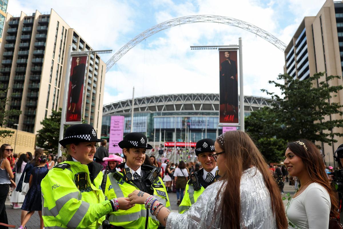 Unas fans intercambian pulseras de la amistad con la policía de Londres antes del primer concierto de la cantante en la ciudad