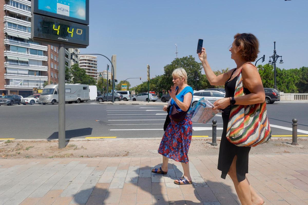 Una mujer toma una foto de un termómetro que marca 44 ºC.
