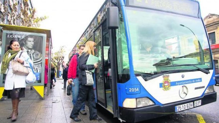 Usuarios subiéndose al autobús en la parada situada frente a la estación central de Avilés.