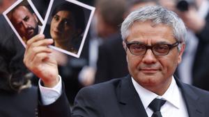 El director de ‘The Seed of the Sacred Fig’, Mohammad Rasoulof, sostiene fotografías de los actores iranís Missagh Zareh y Soheila Golestani, En Cannes este 24 de mayo 