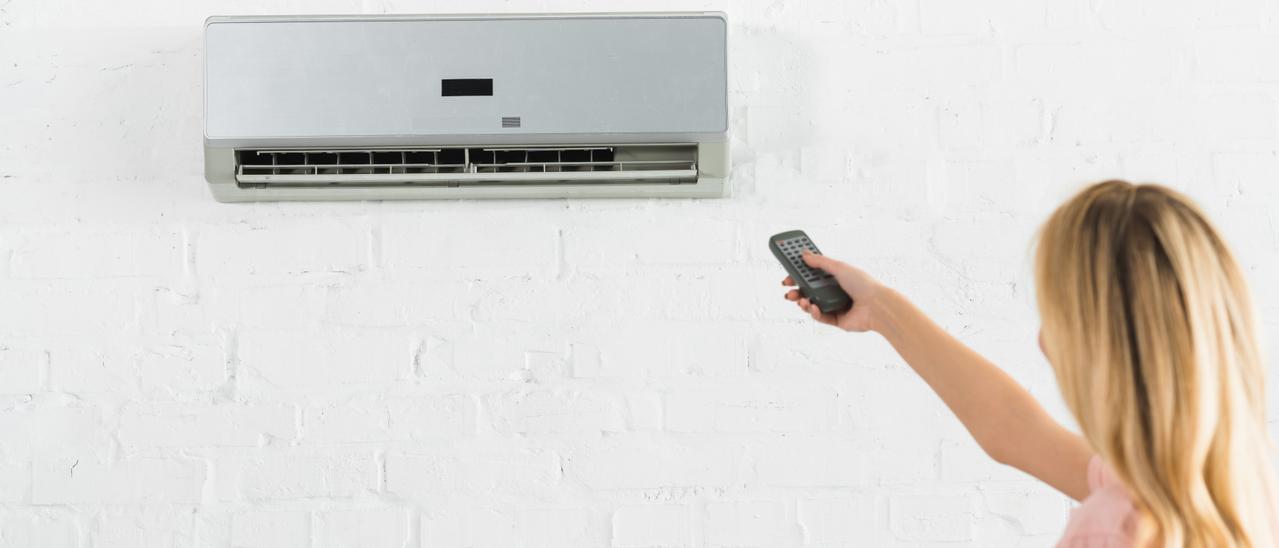 Una vecina regula en su casa un aparato de aire acondicionado.