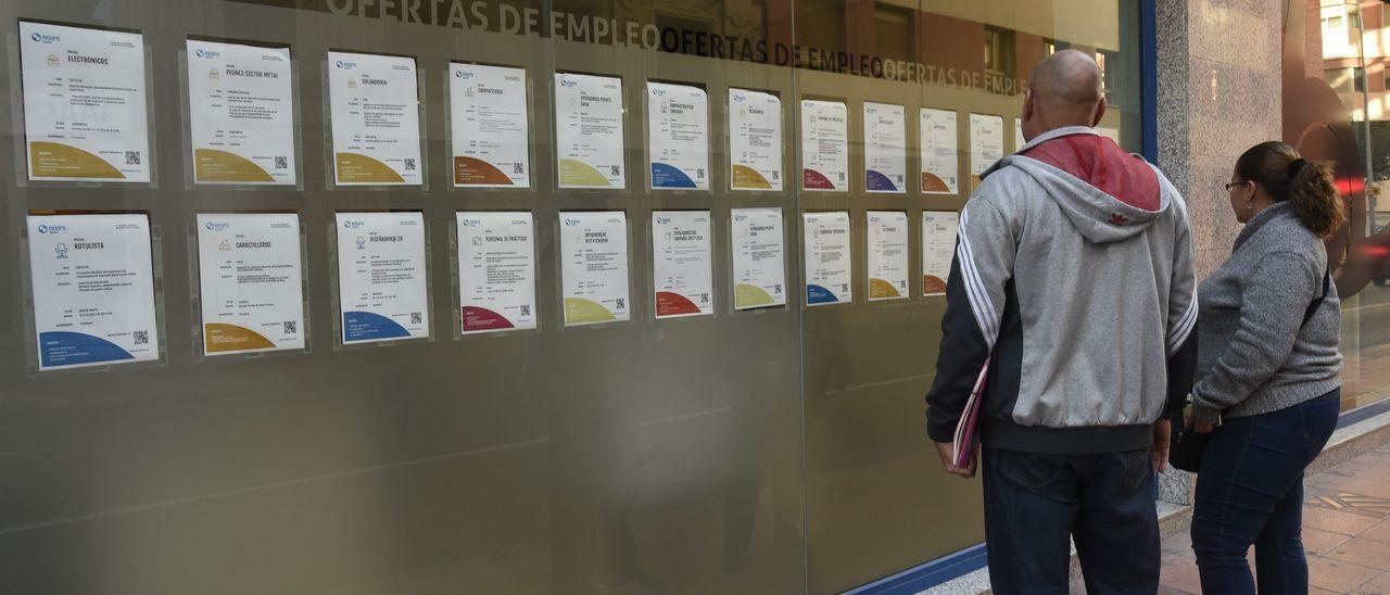 Dos ciudadanos miran las ofertas de empleo en el escaparate de la ETT grupo Noa&#039;s de Castellón.