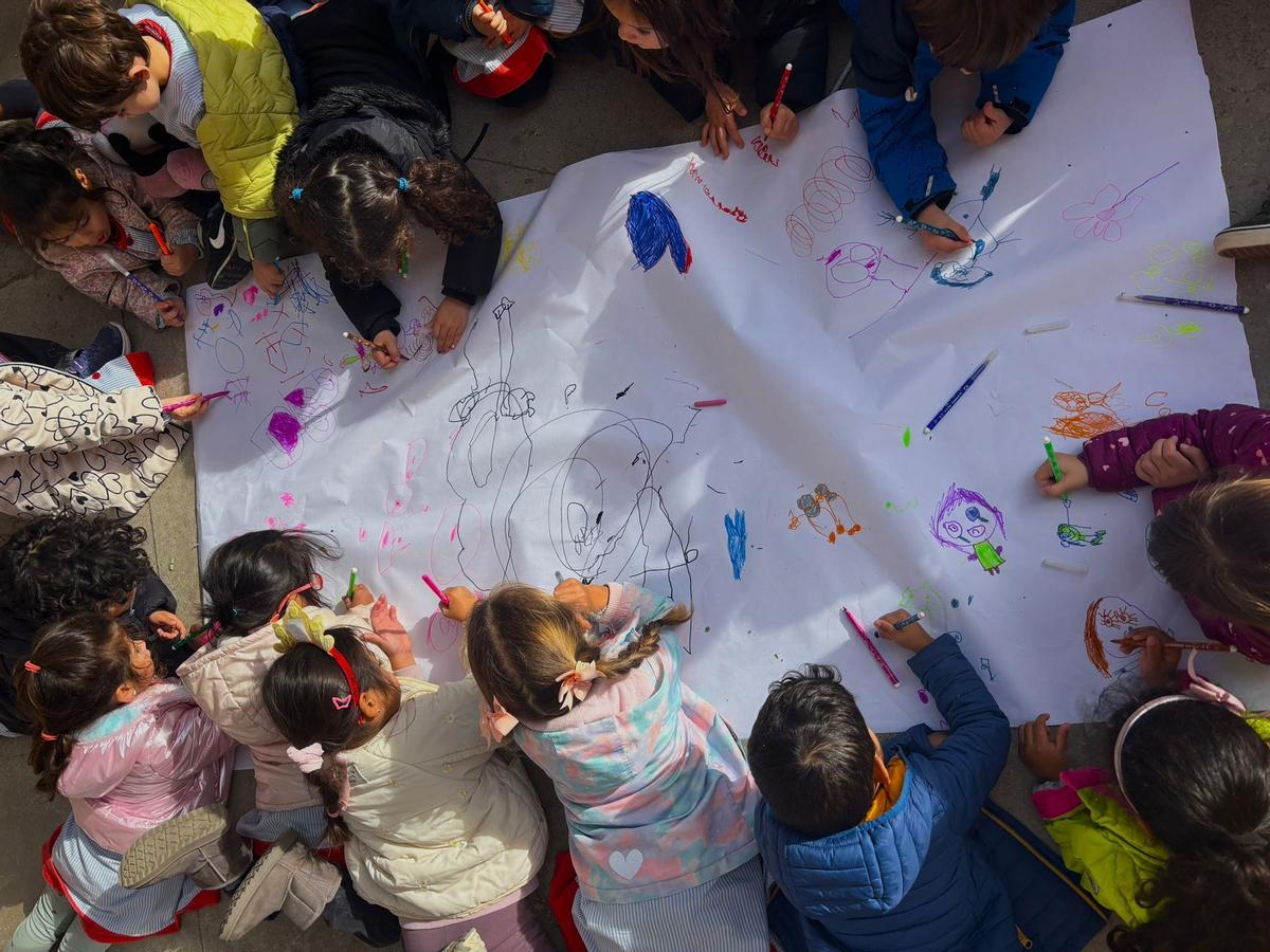 Un grupo de niños pintando sobre un mural.