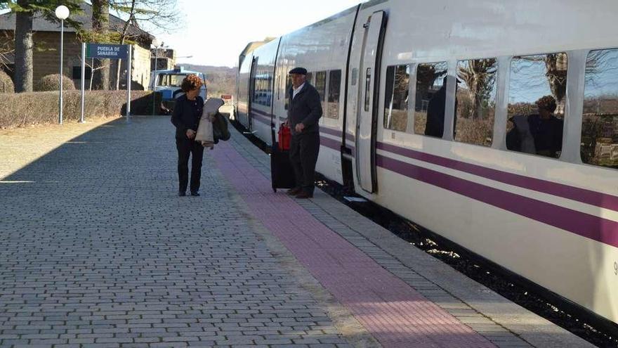 Dos pasajeros descienden del tren en la estación de Puebla de Sanabria.