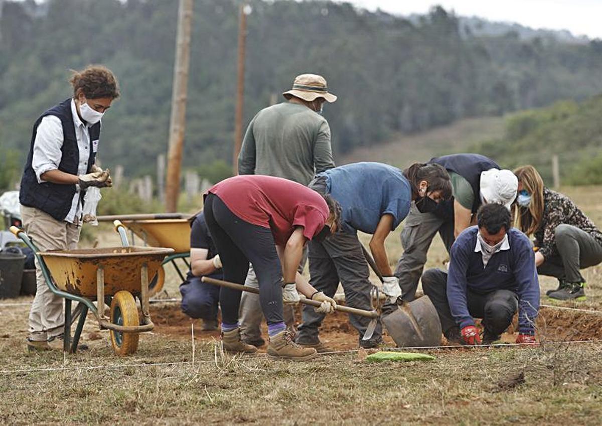 A la izquierda, los arqueólogos Alejandro Sánchez e Irene Faza; y al fondo, los arqueólogos Valentín Álvarez y Adrián Piñán y la restauradora Paula Ablanedo, ayer, iniciando la excavación en La Estaca. Junto a estas líneas, Irene Faza muestra restos extraídos el primer día de la campaña. |