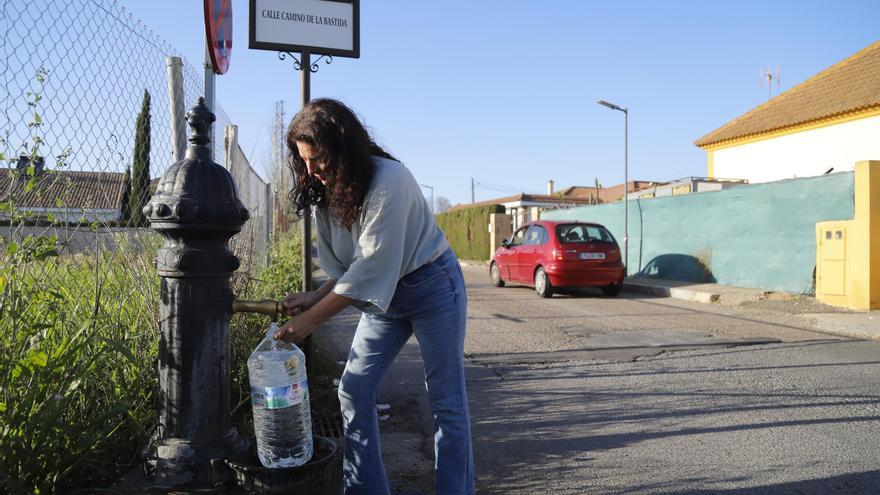 Un hombre llena una botella de agua en una fuente pública de una parcelación.