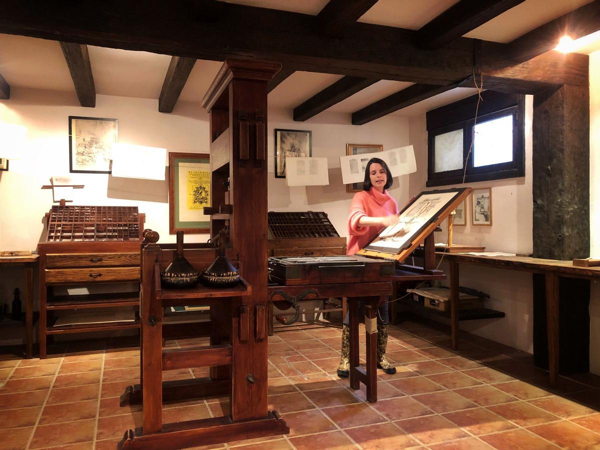 Cristina Esteban, coordinadora de visitas a la imprenta de la Sociedad Cervantina, ante la réplica de la prensa con la que se imprimieron los primeros ejemplares del Quijote en 1605.