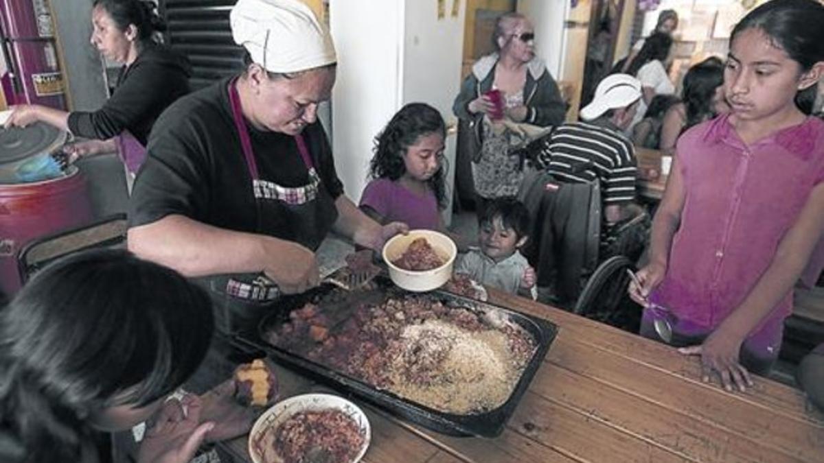 Una voluntaria entrega comida a unos niños en el comedor social de Los Piletones, en Buenos Aires, el pasado día 15.