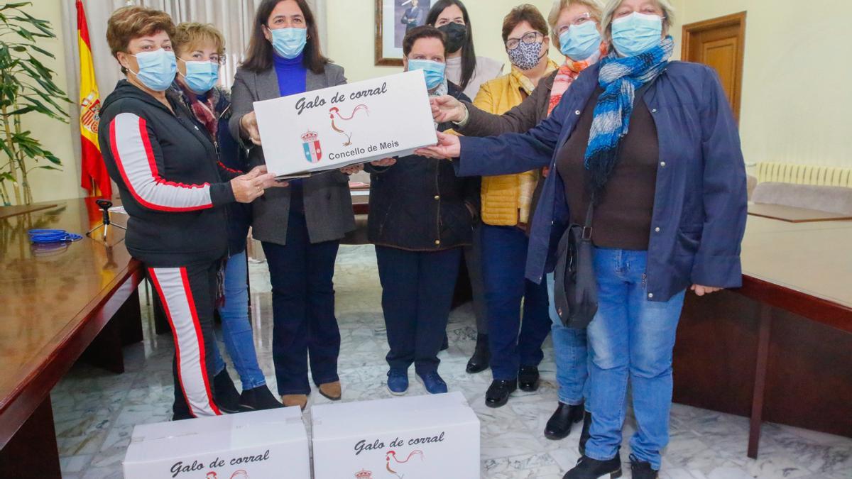 Las criadoras y la alcaldesa, Marta Giráldez (en el centro) muestran las cajas de cartón en las que se envasarán las piezas