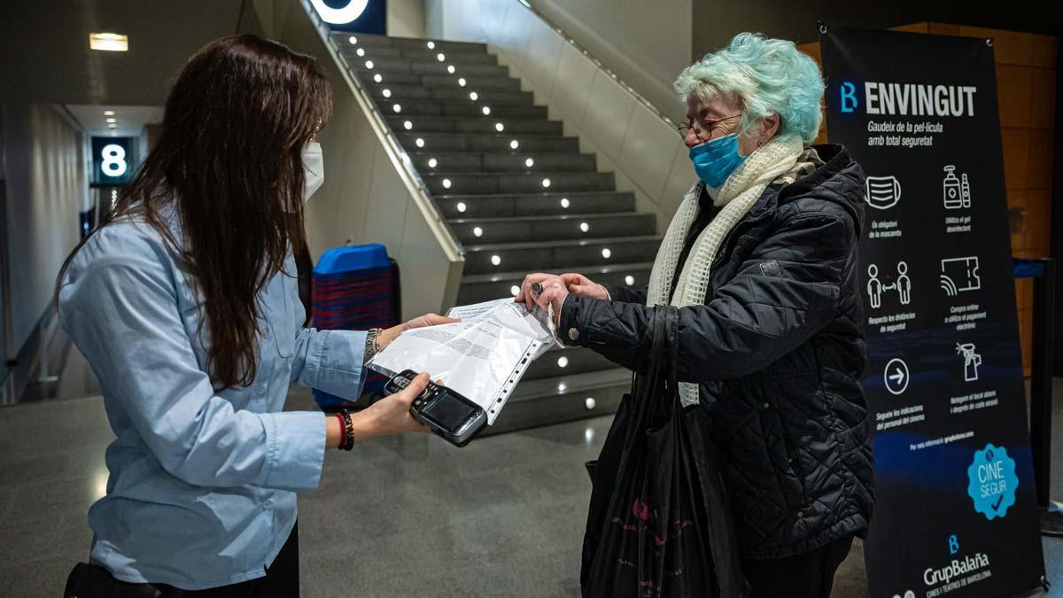 Una mujer muestra su pasaporte covid a su llegada al cine Bosque, en Barcelona