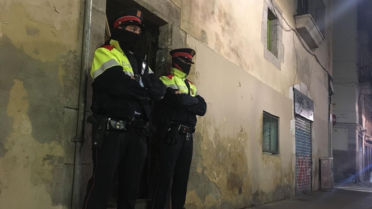 Dos mossos ante el portal de la calle de la Riera Alta donde se ha cometido el crimen.