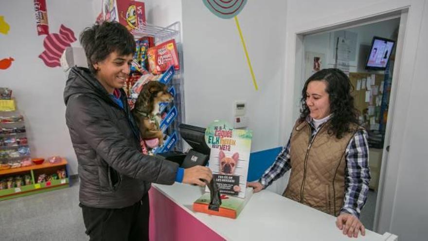 Una propietaria, con su mascota, recoge una bolsa donde depositar las defecaciones, en un comercio de la zona de plaza de Altabix, gracias a los dispensadores del Ayuntamiento.