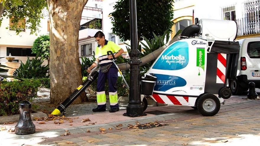 Una operaria limpia una zona verde en el centro de Marbella.